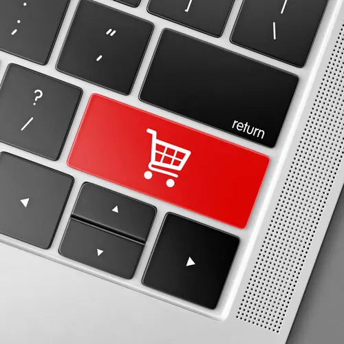 Tecla roja con icono de carrito en teclado, simbolizando diseño web para tiendas online